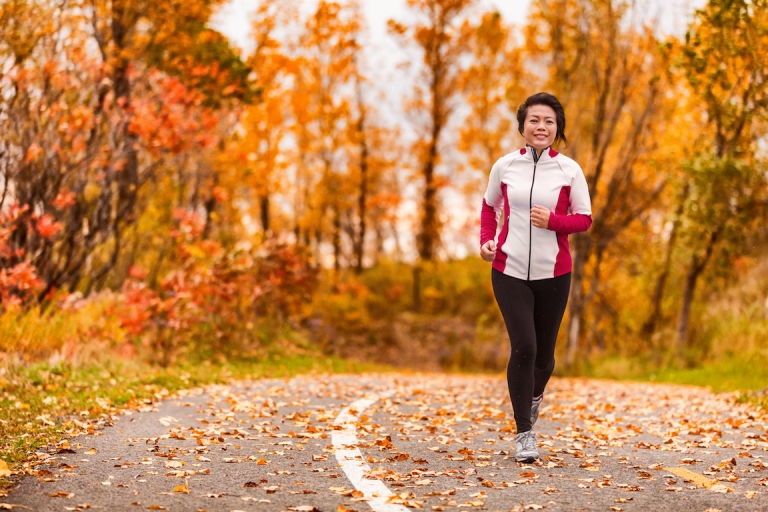 Middle age mature active and healthy Asian woman exercising weight loss body workout jogging running in park path autumn forest. Middle aged lifestyle. Lady in her 50s.